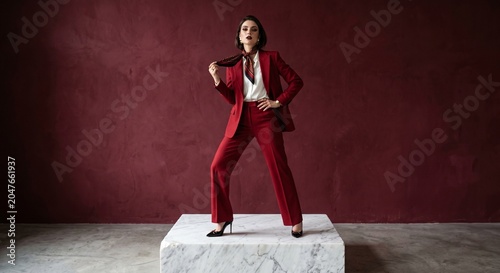 Confident female executive posing in stylish crimson suit indoor