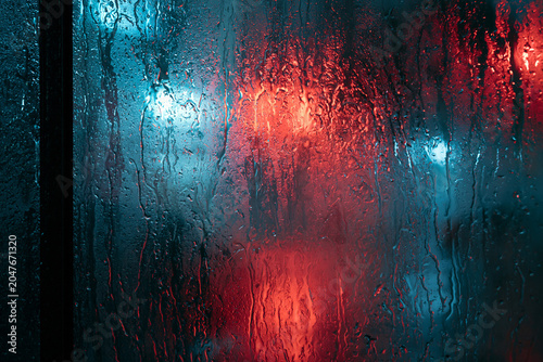 Abstract Urban Night Photography: Blurred Neon Lights and Vibrant Reflections on Wet Glass with Atmospheric Rain and Shadows