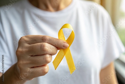Person holds a yellow ribbon between their fingers to symbolize support for sarcoma cancer awareness and patient care.