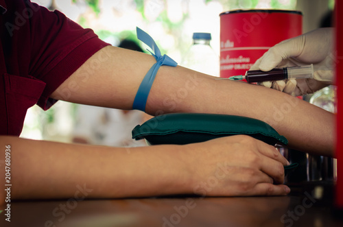 Close up nurse pricking needle syringe in the arm patient drawing blood sample for blood test , Health check