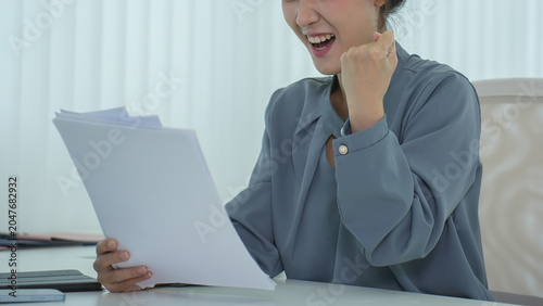 A woman expresses excitement and success while working with documents.