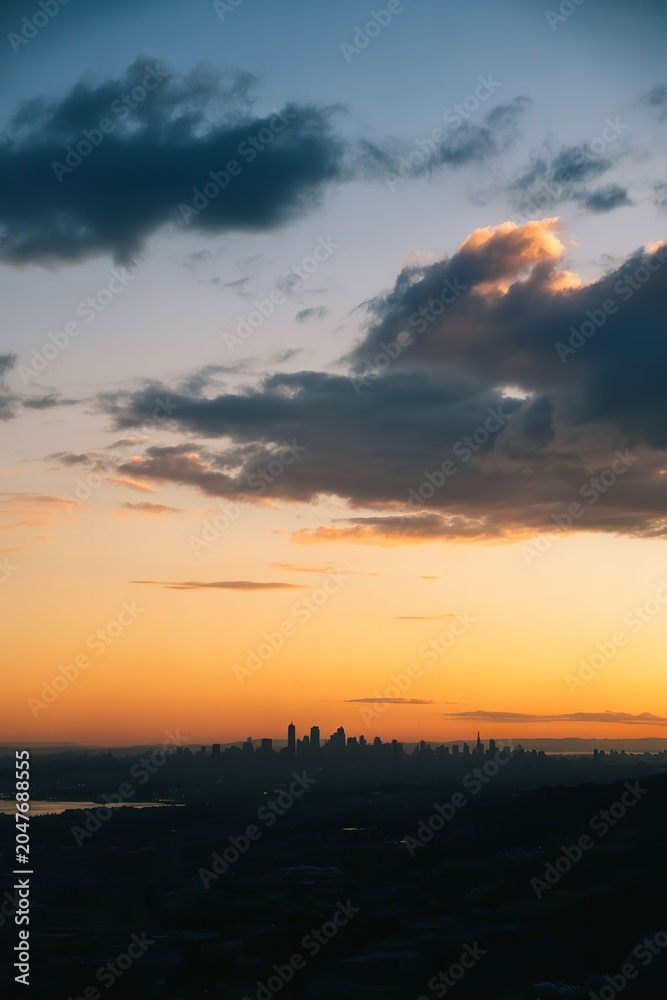 Fototapeta premium Sunset over city skyline with cloudy sky