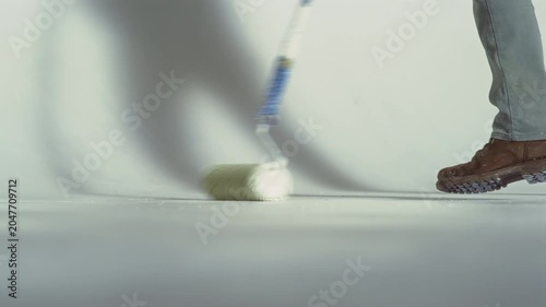 An employee paints the floor of a photo studio cyclorama with white paint