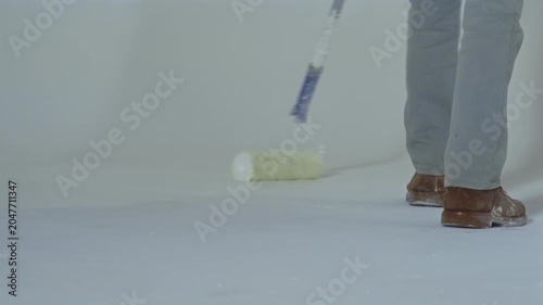 Worker renews paint on cyclorama with white color in photo studio