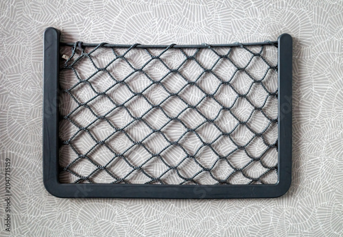Wall mounted storage net pocket with patterned background.