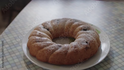 Powdered sugar is sprinkled on top of a freshly baked pie on the kitchen counter