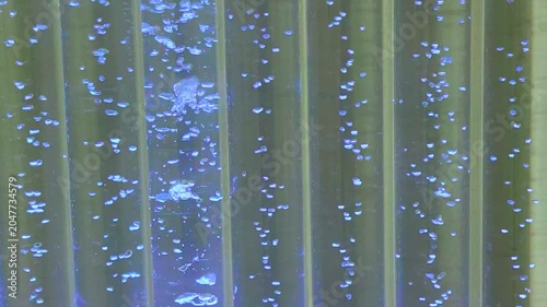 Blue bubbles rising in illuminated water column. Abstract background of liquid texture with vertical streams of air. Sensory equipment for relaxation, therapy and interior decor design.