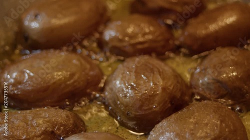 Close-up, potato slices frying in boiling melted butter in a pan