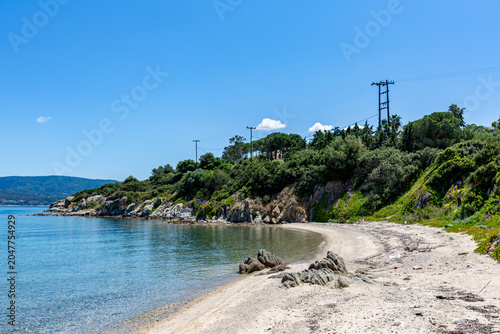 Beach with a boat on the water and a hill in the background, Ammoulliani, Greece
