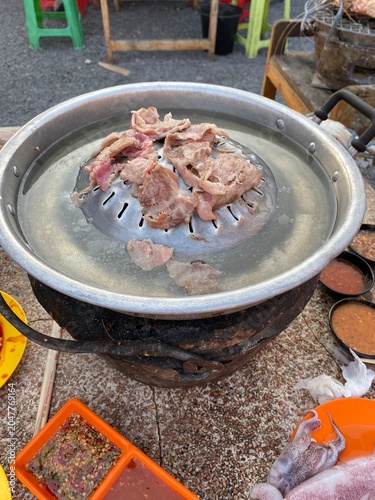 Mookata. Thai barbecue. Thai BBQ. Grilled pork. Thai food. Asian food. Barbecue grill. Hot pot. Dining together. Shared meal. Family dinner. Friends gathering. Restaurant dining.