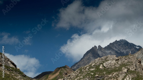 Majestic rocky mountain peaks under a dramatic blue sky with fast-moving white clouds, high alpine landscape in the Loetschental valley, Valais, Switzerland.