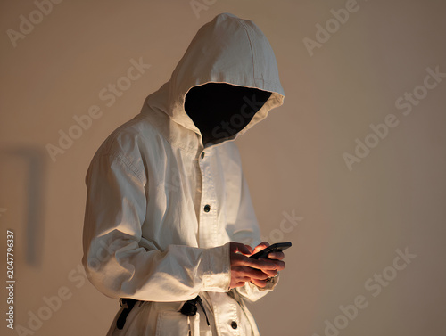 Silhouette-style front view of a figure scrolling on a phone, bright screen lighting their hands and chest, white hooded outfit blending into the background--only the phone and fingertips sharply lit