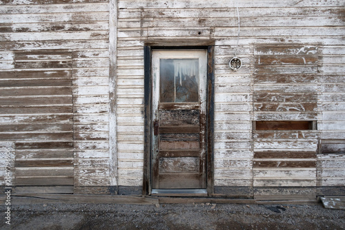 Rustic western ghost town architecture with a central door and distressed white and brown walls, Utah
