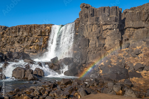 a waterfall over a cliff in Iceland, with the spray forming a rainbow