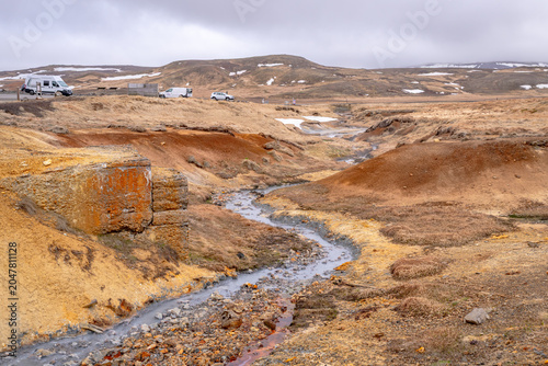 A stream of geothermally heated water flows through a sulfuric landscape in Iceland