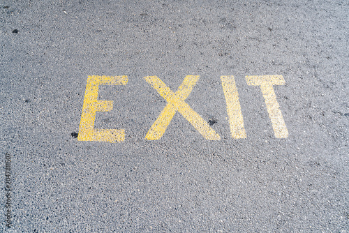 Принти на полотні Yellow EXIT text painted on gray asphalt road surface closeup top view