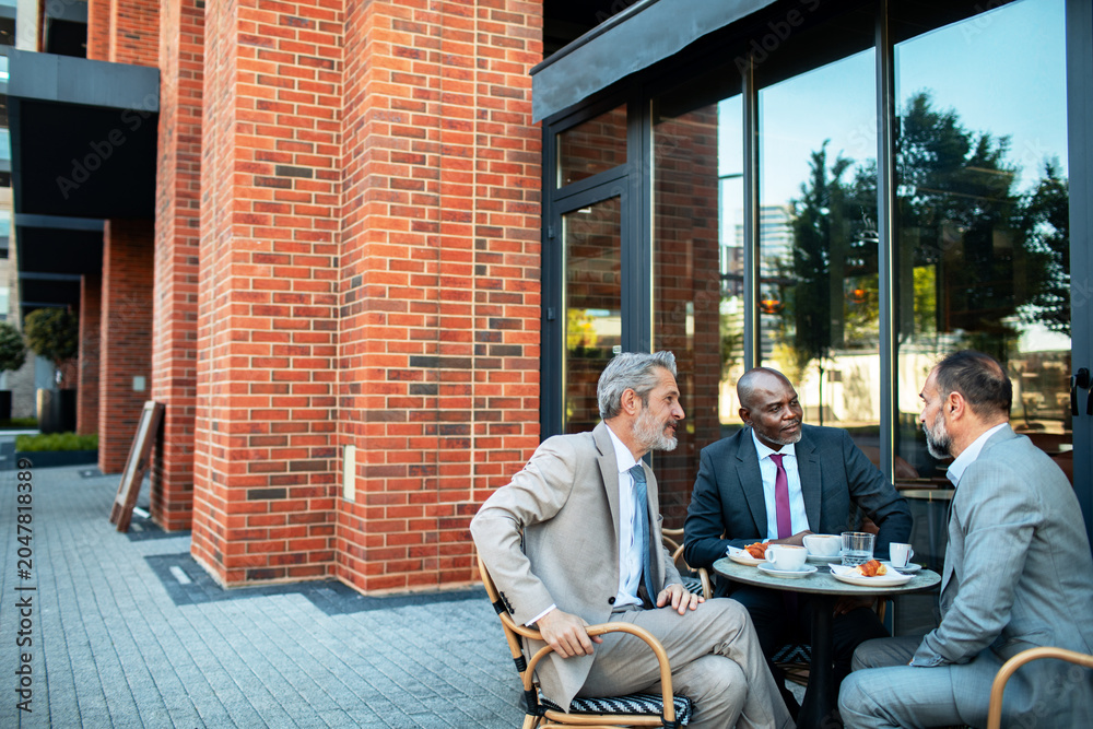 © Marko Geber - Three executives meeting over coffee at outdoor cafe