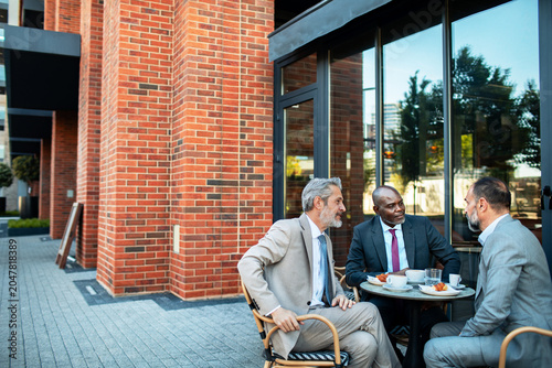 Three executives meeting over coffee at outdoor cafe