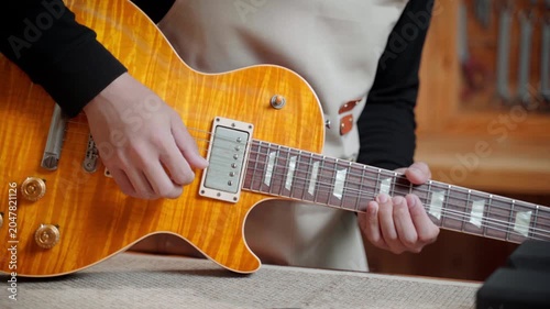 Close Up Guitar Repairman Adjusting Electric Guitar Strings at Workshop
