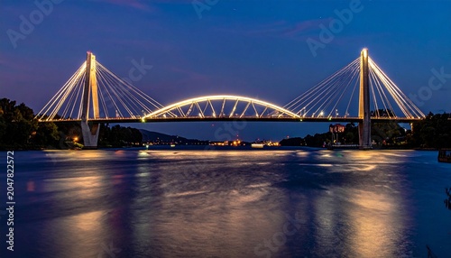 Illuminated bridge over water at night with reflections.