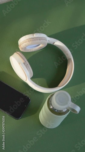 Vertical video: Rotating camera revealing headset on green mat, documenting phone and water bottle