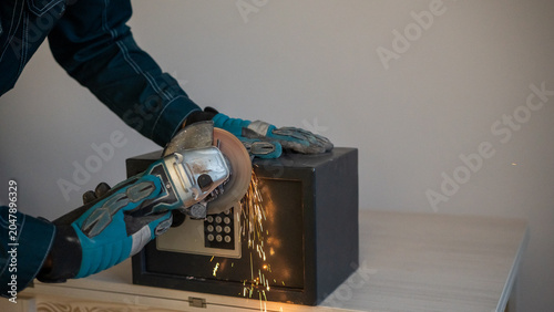 Foto A man breaks into a safe with a grinder.
