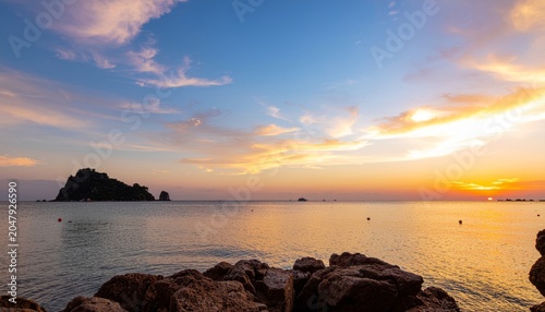 Beautiful sunset over the calm ocean with island silhouette.