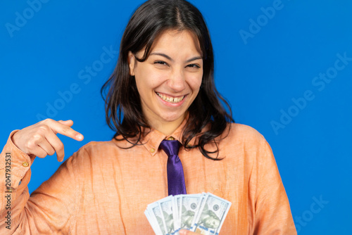 Happy woman holding money pointing to copy space