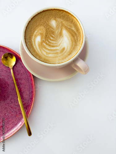 Elegant cappuccino cup, pink saucer and golden spoon flat lay with negative space for text. High quality photo