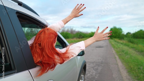 Foto Young girl with red hair catches wind from car window