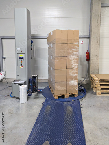 Stacked Cardboard Boxes On Pallet Being Wrapped On Stretch Film Machine In Warehouse Logistics