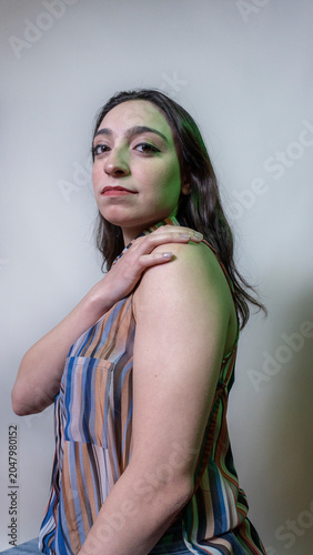 Side view of tired young woman looking at camera over plain background