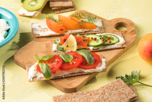 Fresh crunchy rye crispbreads with different toppings on green table, top view