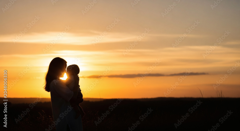 Fototapeta premium Mother holding baby silhouette during golden hour sunset in an open field representing family bonding and maternal care outdoor