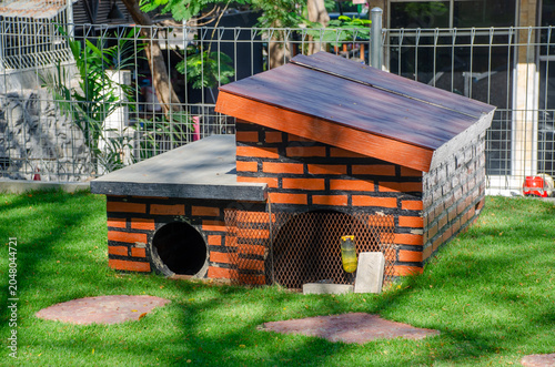 Canvas-taulu Outdoor Animal Shelter with Brick Pattern and Wooden Roof on Green Grass