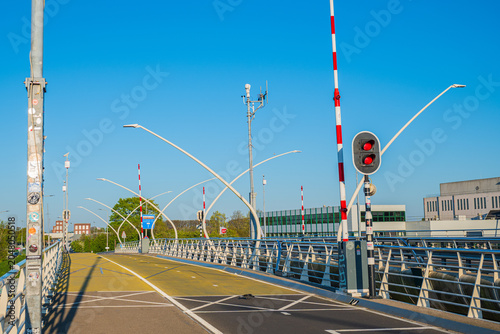 фотографія Modern drawbridge with red traffic light and open barriers against clear blue sk