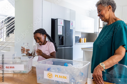 Quadro su tela African grandmother and youth female sorting recycling in home kitchen using GLA