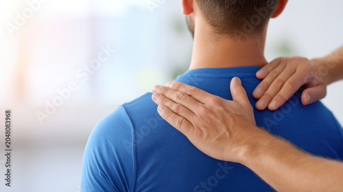 Physiotherapist examining male back in clinic, manual therapy for spine pain and muscle tension with hands on shoulder and neck