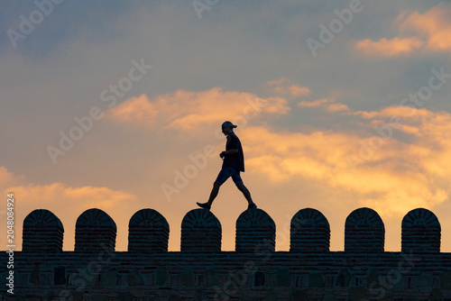 Western Asia, South Caucasus, Republic of Georgia, Tbilisi. Silhouette of person running or jumping along crenulated wall at Narikala Fortress.
