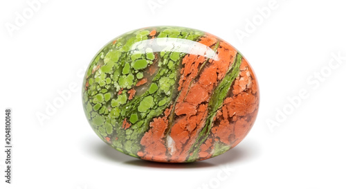 A polished oval stone with green and orange patterns.