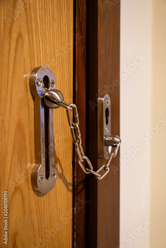 Bild auf Leinwand A metal chain lock secures a wooden door for added safety.