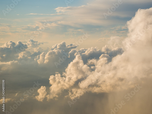 Massive expanding cumulus storm cloud glowing with intense golden sunlight in the blue evening sky prior to a thunderstorm.