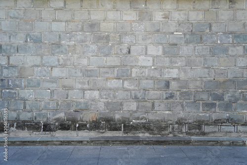 A fragment of a street city gray brick wall of a building and an paving stones. Building's facade.