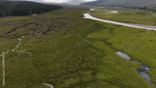 Bild auf Leinwand Aerial View of Winding River Through Green Highland Valley