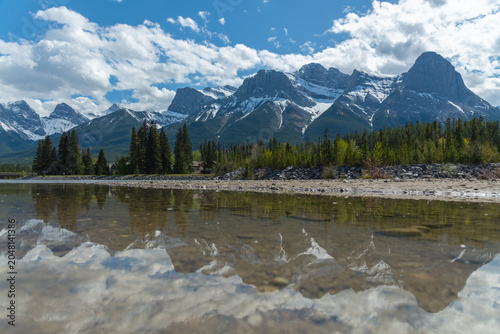 Stunning summertime views in Canada along the Bow River in the town of Canmore with stunning, snow capped peaks in small tourist town. 