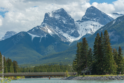 Stunning summertime views in Canada along the Bow River in the town of Canmore with stunning, snow capped peaks in small tourist town. 