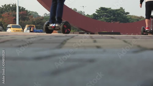 사람 세그웨이 모빌리티 광장 공원 산책 일상 여가 라이프스타일 디테일 자재: 야외 광장에서 스마트 모빌리티 세그웨이를 타고 나란히 주행하는 사람들의 뒷모습과 일상을 담은 로우앵글 숏입니다.