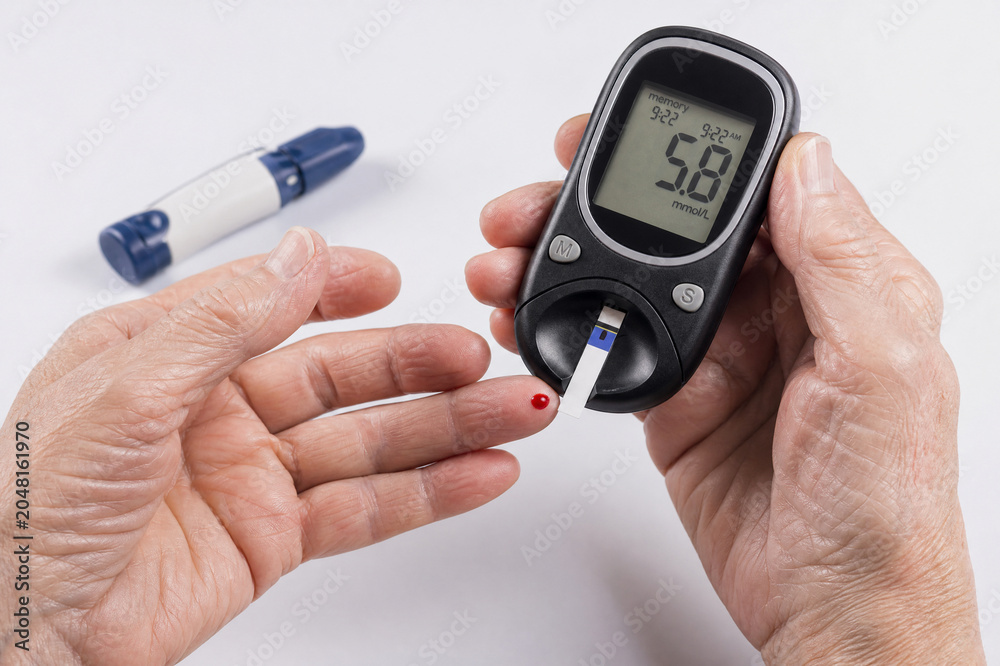 Fototapeta premium Diabetic person checking blood sugar level with glucose meter