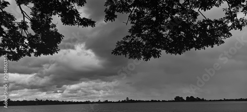 Bild auf Leinwand Dramatic sky with dark storm clouds above the water