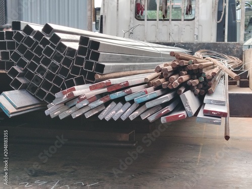 Heavy metal steel profiles and rods prepared for transport and distribution at a construction site logistics yard.